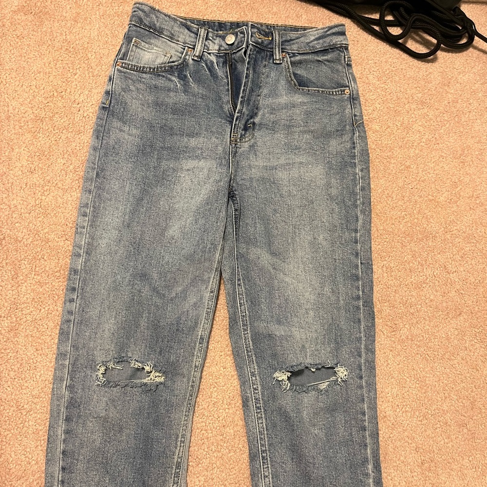 Blue jeans with rips knee rips.